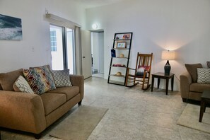 A living room with a sofa, a chair, a side table, a lamp, and a bookshelf.