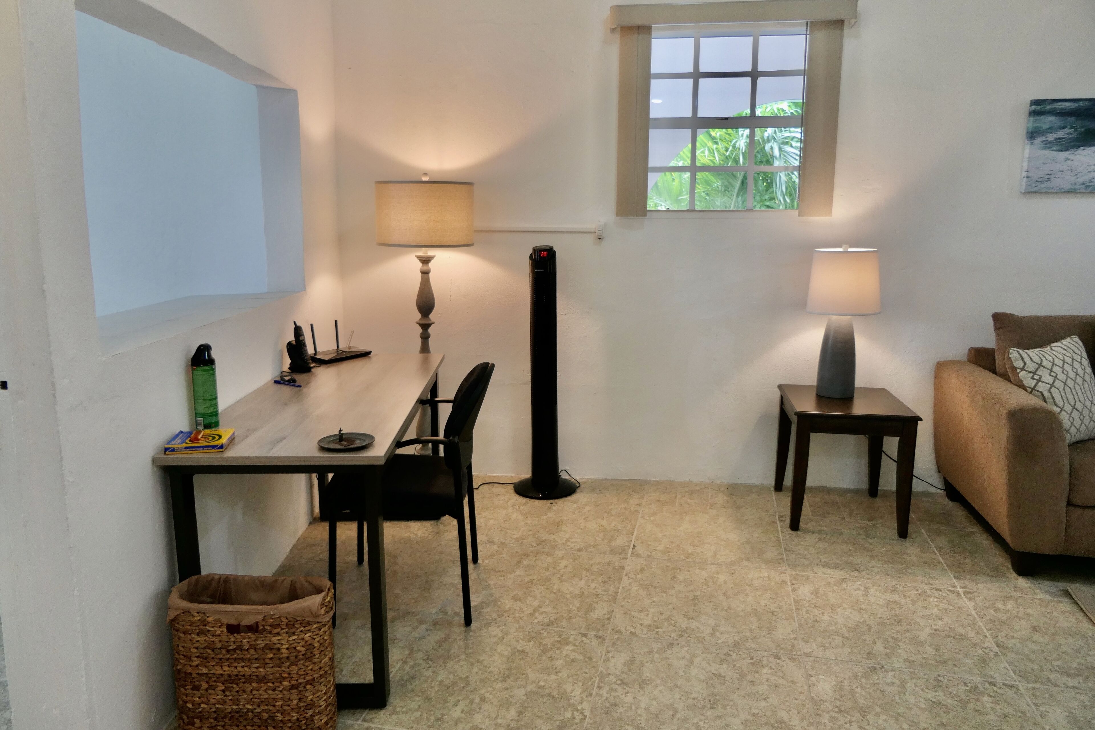 Ein kleiner, gut beleuchteter Raum mit Esstisch, Stühlen, einer Stehlampe, einem Fenster und einer Couch.
