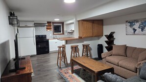 A compact living space with a kitchenette, a sofa, a coffee table, and a bar stool. - Cute Southside Private Apartment in Bozeman (Bozeman)