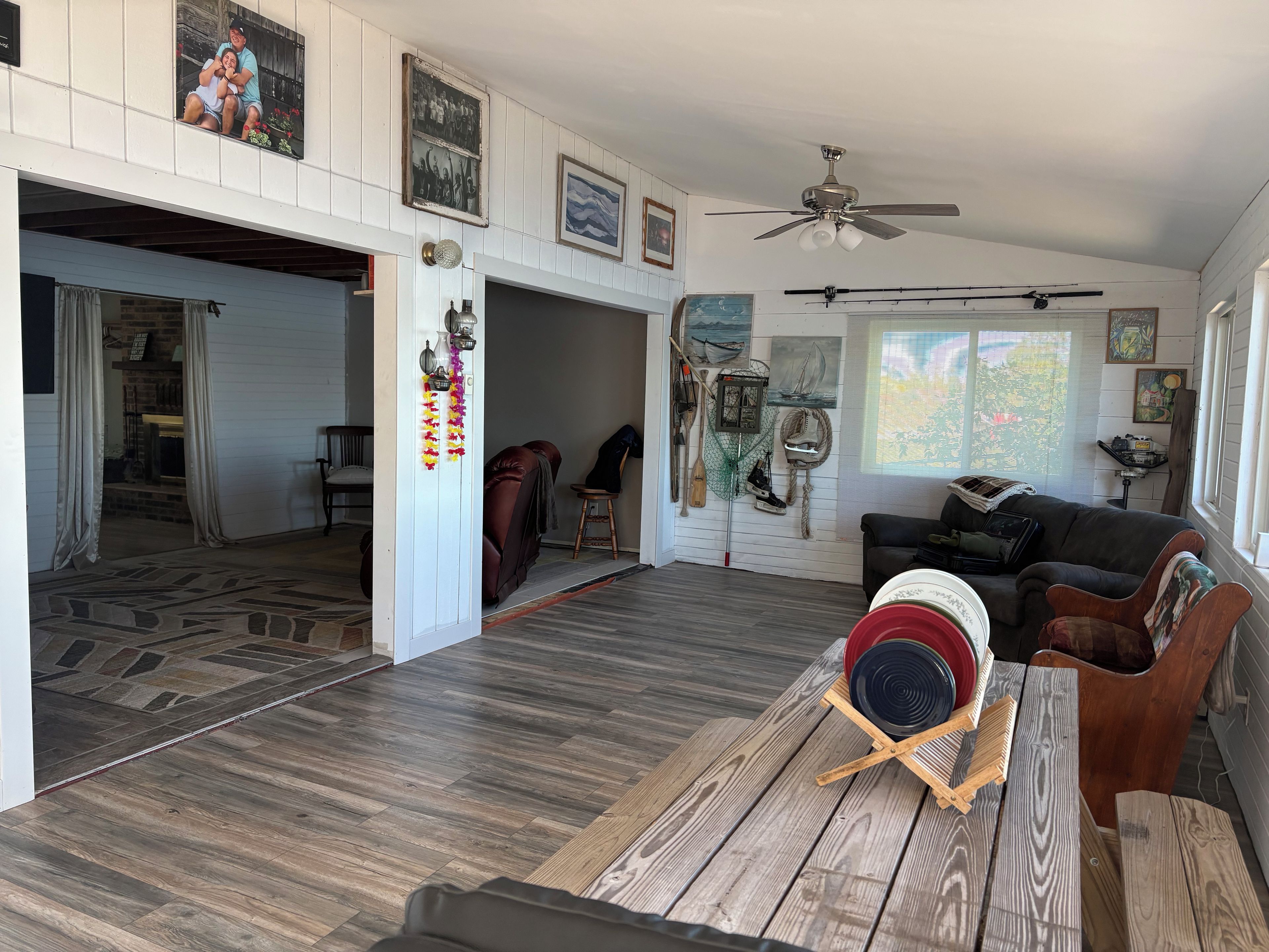 A spacious living area with a wooden floor, a ceiling fan, and a dining table with a red bowl.