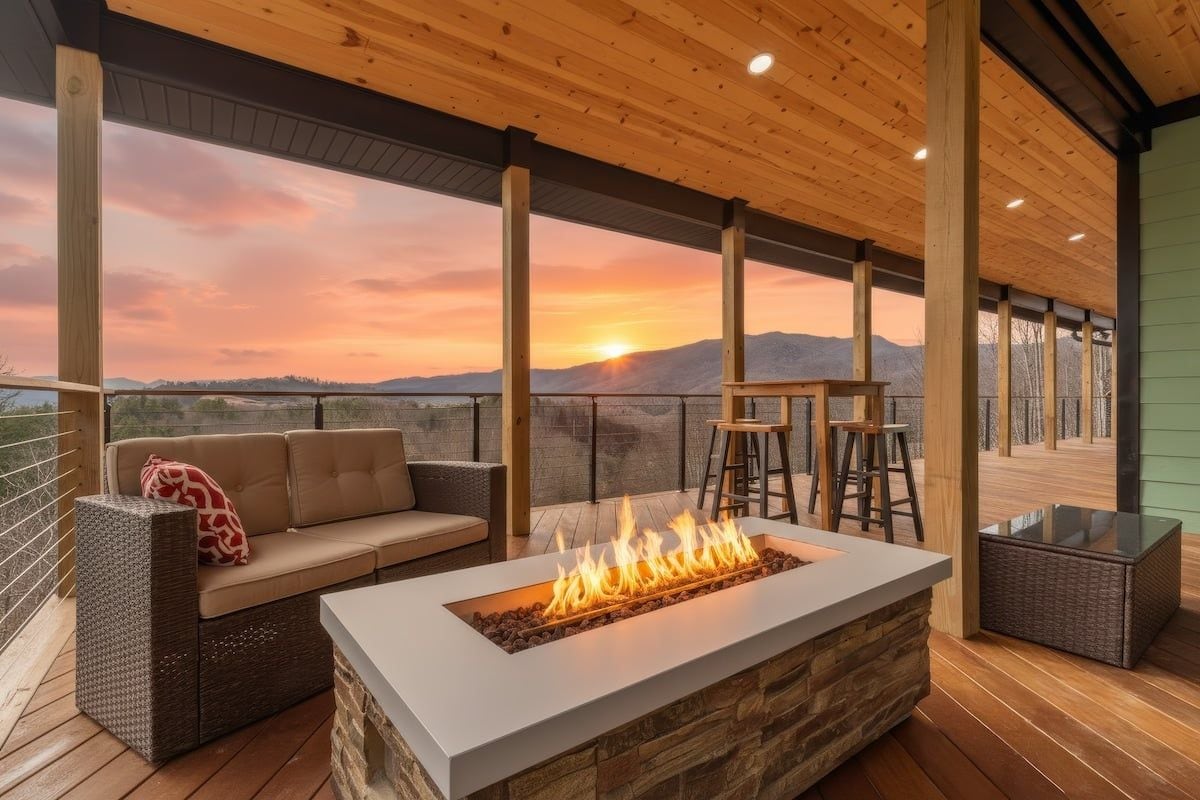 An outdoor seating area with a fire feature, wooden deck, and a view of the sunset.