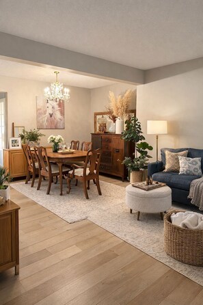 A dining area with a wooden table and chairs, a chandelier, and a blue sofa. - Stylish Calgary Haven in Cougar Ridge – Quiet Street, Close to Parks & C‑Train (Calgary)