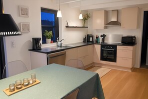 A modern kitchen with a dining area, a coffee maker, a microwave, and a sink. - Lovely holiday home near beach with sauna (Otterup)