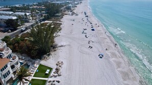 Ein Strandresort mit einem langen Sandstrand, einem Poolbereich mit Liegestühlen und Blick auf den Ozean.