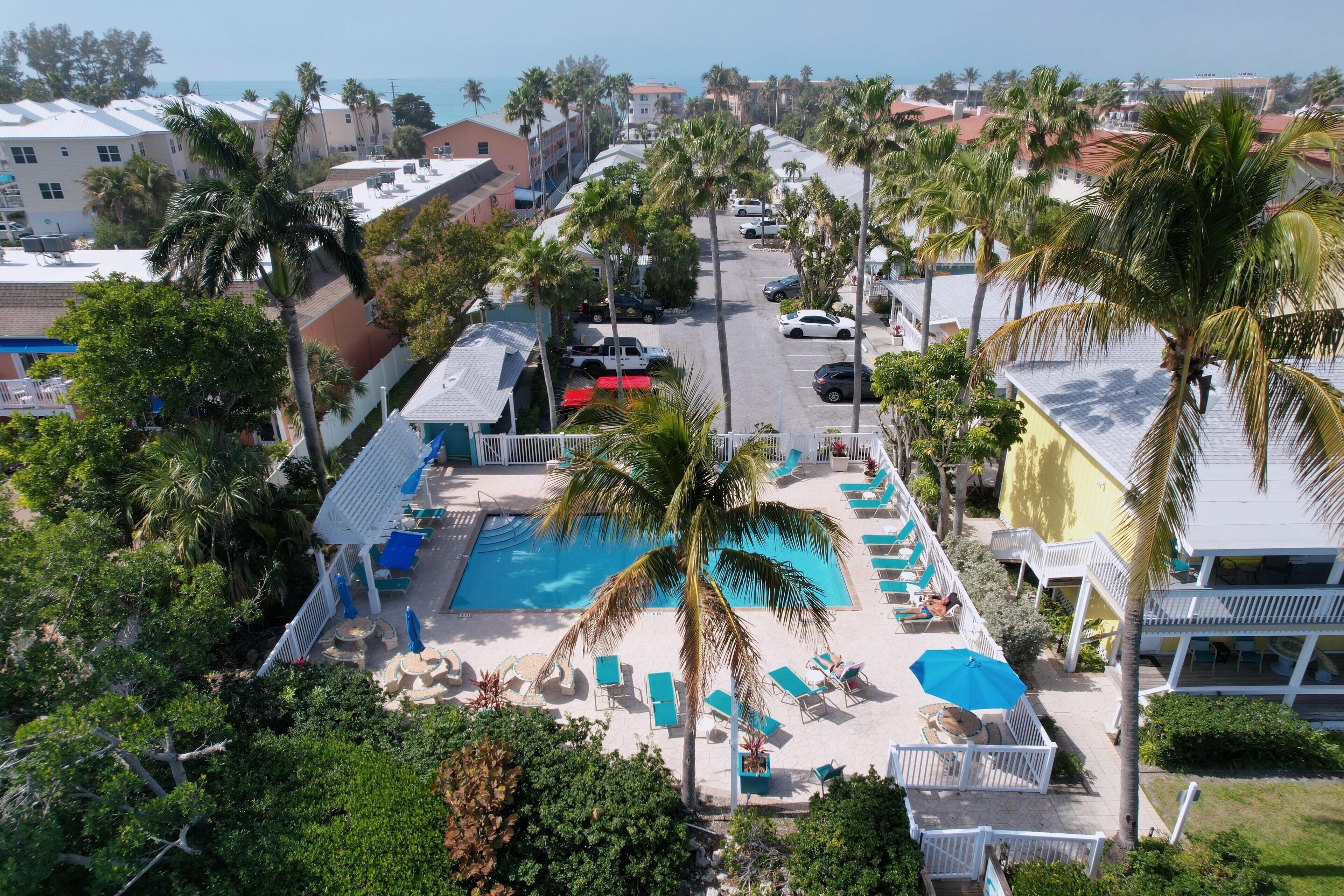 Un resort con piscina, palmeras y vista al océano.