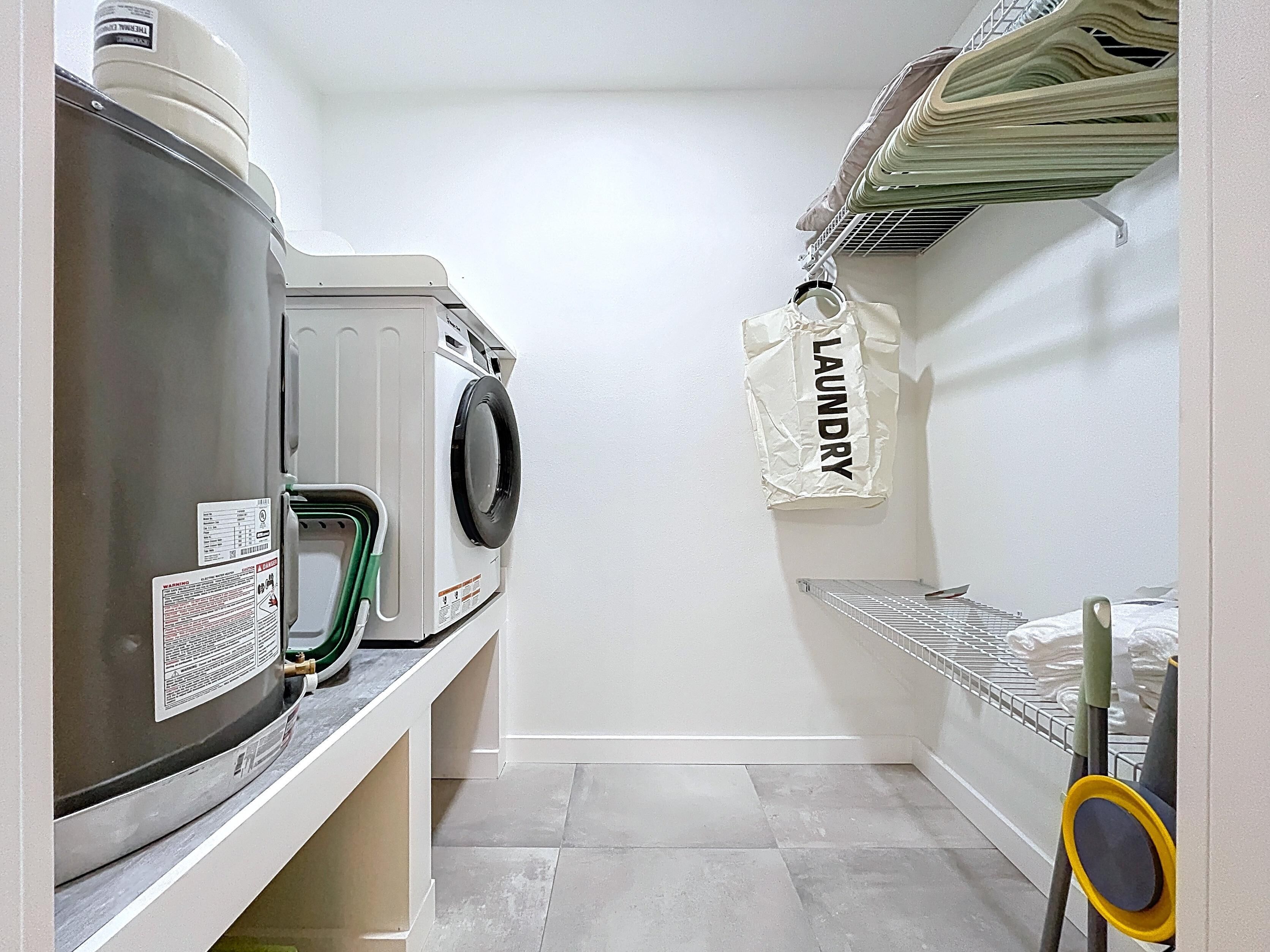 A laundry room with a washing machine, dryer, and a hanging rack.