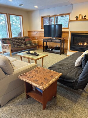 Una sala de estar acogedora con sofá, mesa de centro, televisor y chimenea.