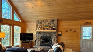 A cozy living room with a stone fireplace, wooden walls, and a television. - 
Picturesque 4 - Bedroom Lakefront Cabin on the popular Minong Flowage (Minong)
