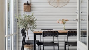 Uma sala de jantar com uma mesa, cadeiras, uma planta em vaso e uma cesta fixada na parede.