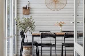 A dining area with a table, chairs, a potted plant, and a wall-mounted basket.