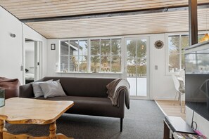 A modern living room with a sofa, a coffee table, a TV, and large windows.