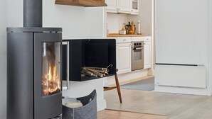 A modern kitchen with a wood-burning stove, white cabinets, and a refrigerator. - Bright and spacious holidayhome near Vejby Strand (Vejby)
