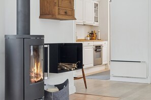 A modern kitchen with a wood-burning stove, white cabinets, and a refrigerator. - Bright and spacious holidayhome near Vejby Strand (Vejby)