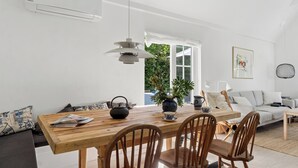 A modern living space with a wooden dining table, chairs, a sofa, and a potted plant. - Bright and spacious holidayhome near Vejby Strand (Vejby)