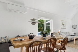A modern living space with a wooden dining table, chairs, a sofa, and a potted plant. - Bright and spacious holidayhome near Vejby Strand (Vejby)
