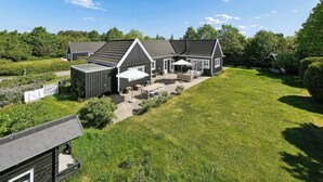 A large house with a spacious backyard, a covered patio, and a fenced garden area. - Bright and spacious holidayhome near Vejby Strand (Vejby)