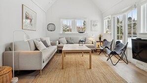 A modern living room with a sofa, a coffee table, and a TV. - Bright and spacious holidayhome near Vejby Strand (Vejby)
