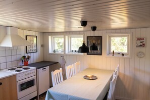 Een keuken met witte kastjes, een fornuis en een eettafel met stoelen.