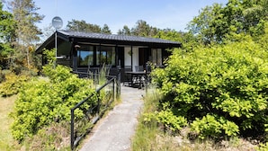 Ein modernes Haus mit einem Weg, der zu einer Veranda mit Sitzgelegenheit führt.