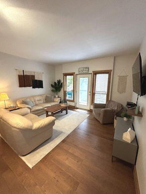 Un salon avec un canapé, une table basse et un téléviseur fixé au mur.