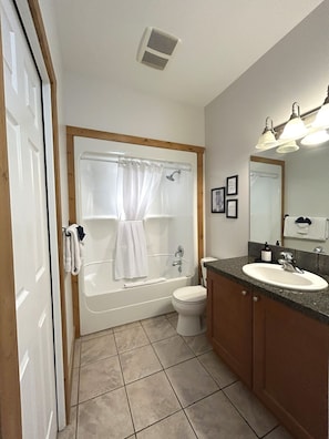 Une salle de bain équipée d’une baignoire, de toilettes, d’un lavabo et d’un rideau de douche.