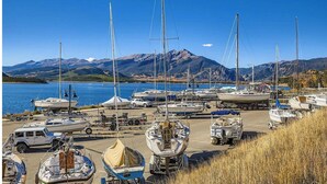 A marina with boats docked, a trailer, and a vehicle. - Dillon Lakefront Luxury w Iconic Mountain Views. Walk to Marina & Amphitheater (Dillon)