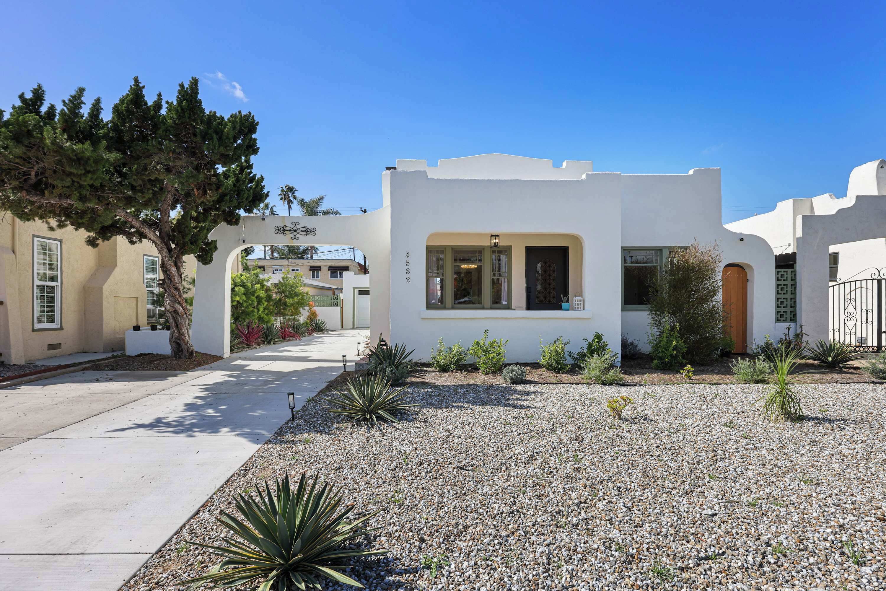 Une maison moderne à l’extérieur blanc, avec le numéro « 4582 » bien visible et une allée gravillonnée.