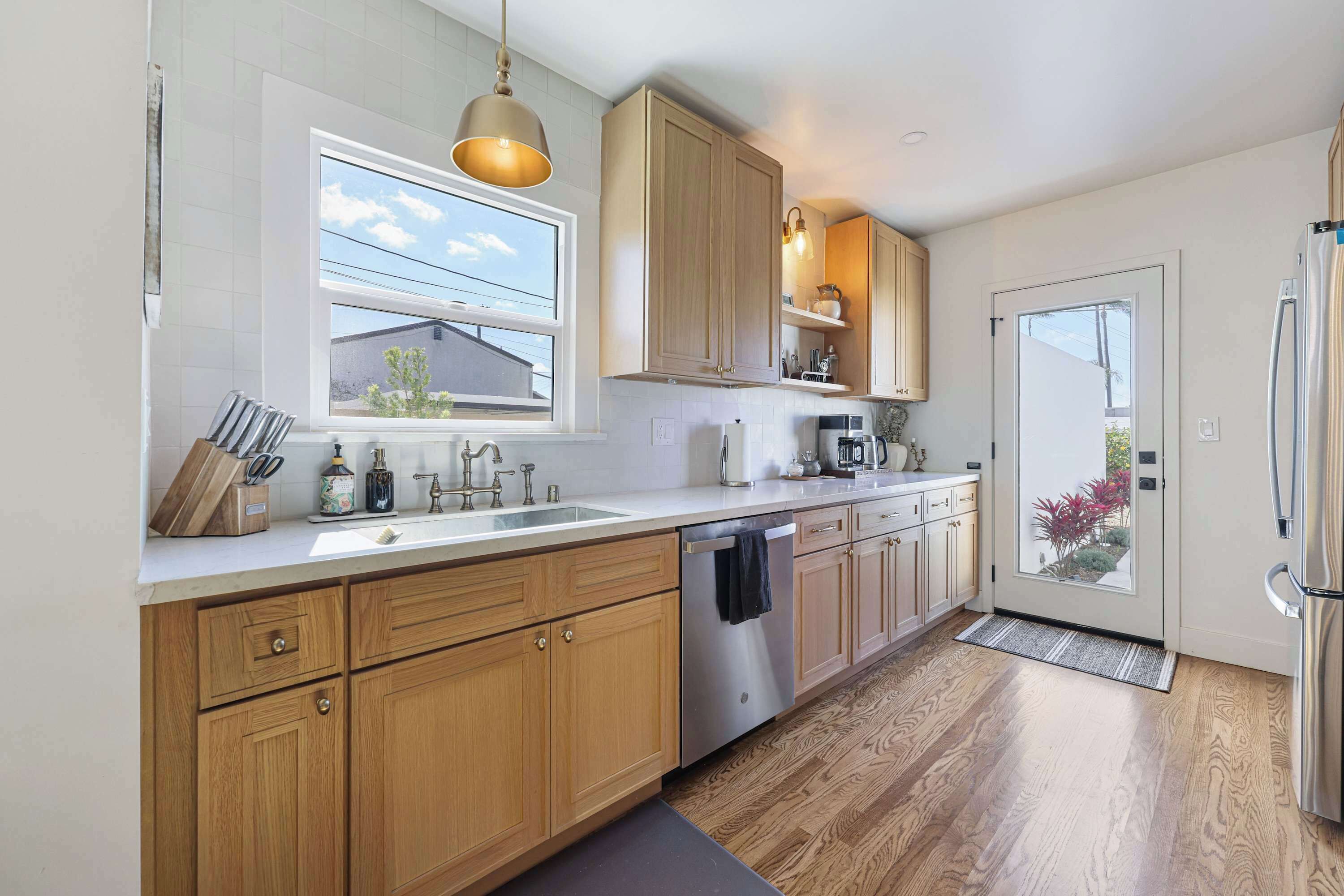 A modern kitchen with wooden cabinets, stainless steel appliances, and a large window providing natural light.