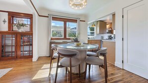Un coin repas avec une table ronde, six chaises et un lustre.