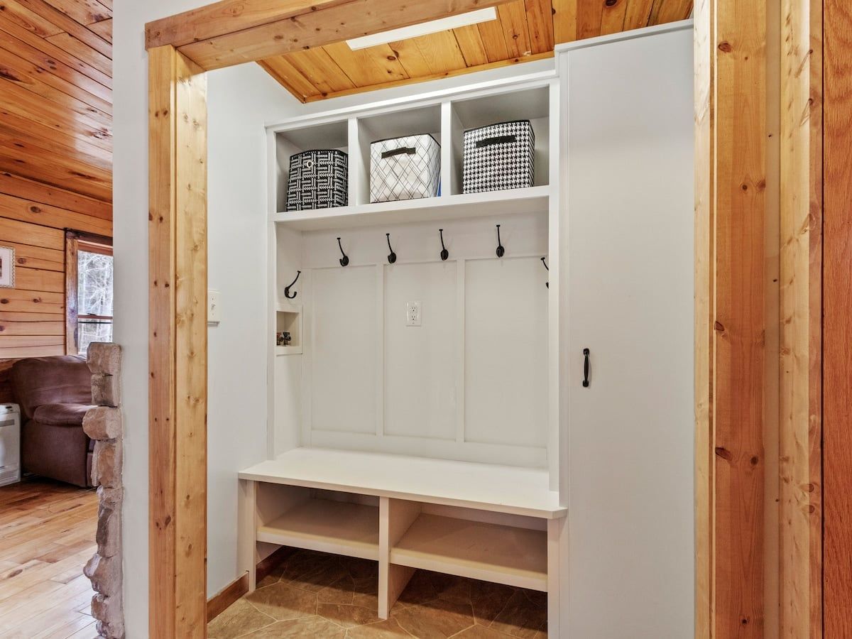 A wooden-paneled room with a white bench and storage baskets.