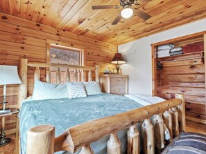 Ein schlichtes Schlafzimmer im Chalet-Stil mit Bett, Nachttischen, einer Lampe und einem Holz-Kopfteil.