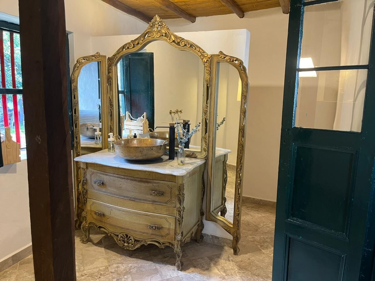 Een vintage kaptafel met versierde gouden spiegels en een wasbak.