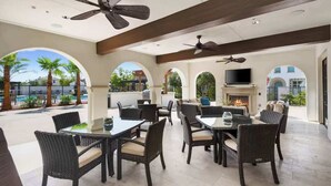 Un patio al aire libre con mobiliario de mimbre, ventiladores de techo y una chimenea.