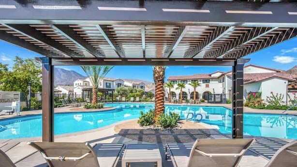 Zona de piscina con sillones de descanso y una pérgola.