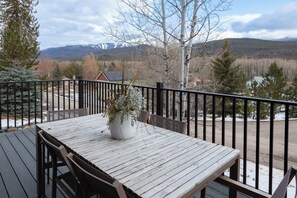 A wooden deck with a table and chairs, a potted plant, and a view of a snowy mountain range. - Stunning Whitefish Retreat w/ Ski Views, Multiple Decks, Open Living & Near Glacier Adventures (Whitefish)