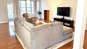 Een moderne woonkamer met een modulaire bank, een televisie en een potplant.