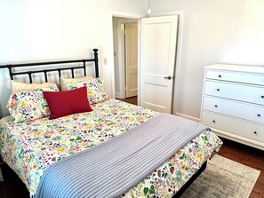 Um quarto com cama, cômoda e porta.