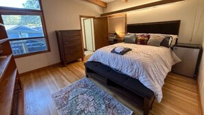 A bedroom with a bed, wooden floor, a dresser, a window, and a door. - Golf and Campus Getaway  EV, Near Hospitals- 3 Bedroom, 2.5 Bath (Memphis)