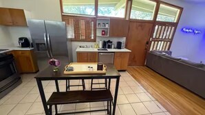 A compact kitchen with a refrigerator, stove, and dining table with a bench. - Golf and Campus Getaway  EV, Near Hospitals- 3 Bedroom, 2.5 Bath (Memphis)