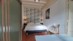 Ein Schlafzimmer mit Bett, Stuhl, Nachttisch und Wand mit einem Blattmuster.