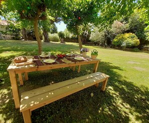 Una mesa de picnic de madera con bancos, platos, vasos y comida.