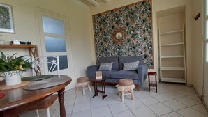 Ein Wohnzimmer mit grauem Sofa, kleinen Hocker, einem Holztisch und einer Zierwandverkleidung.