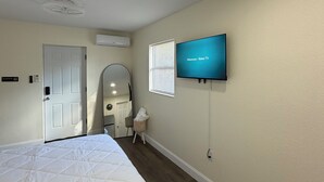 Une chambre d’hôtel équipée d’un lit, d’un téléviseur fixé au mur, d’une porte et d’un appareil de climatisation.