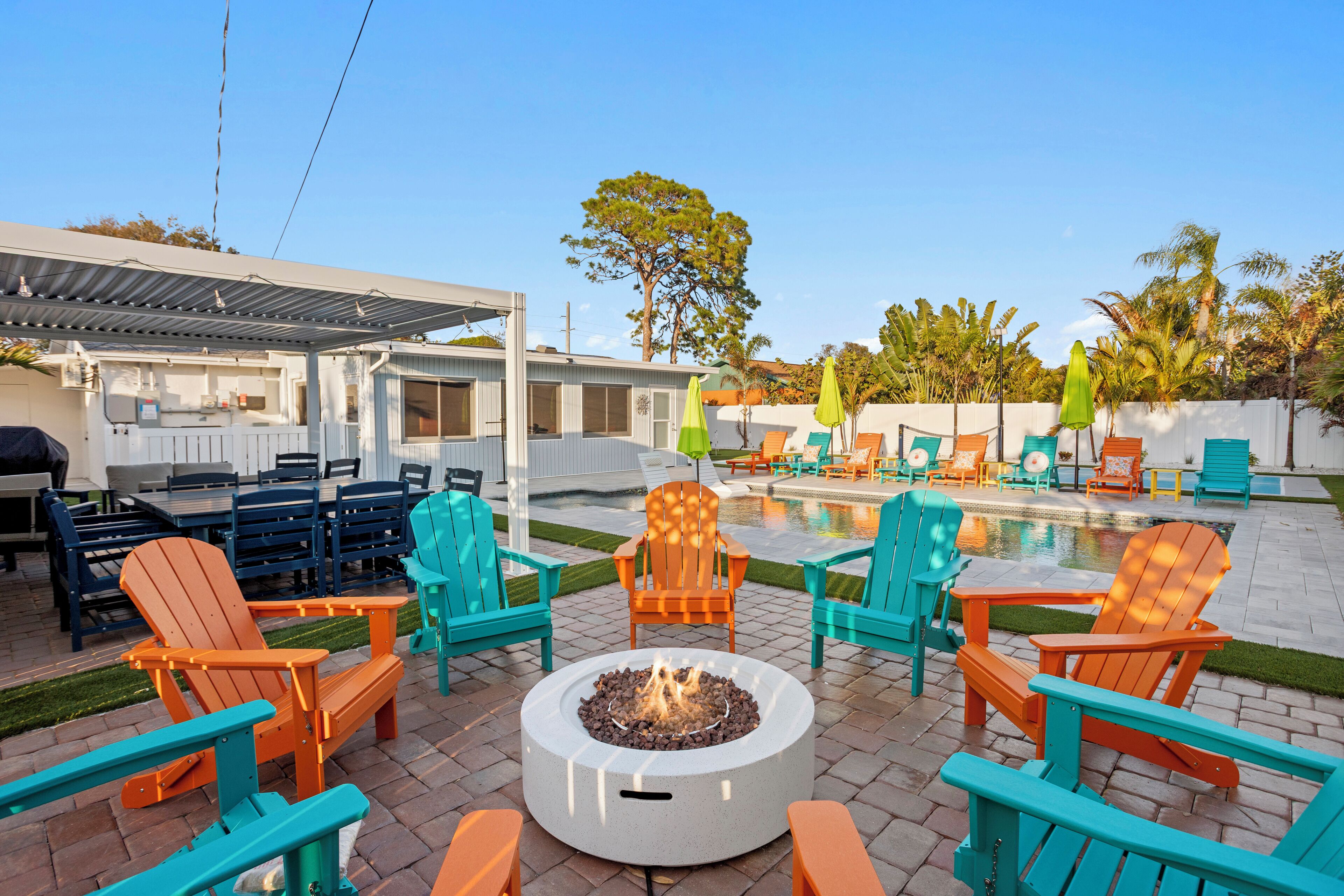 An outdoor patio area with a fire pit, seating, and a pool.
