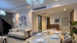 A modern dining area with a marble table, cushioned chairs, and a chandelier.