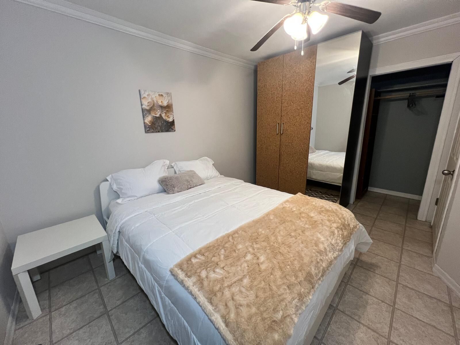 A bedroom with a bed, a nightstand, a wardrobe, and a ceiling fan.