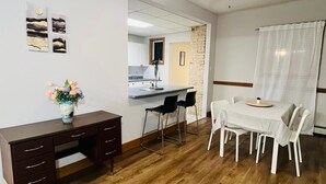 Een eethoek met een tafel en stoelen, een plafondventilator, en een keuken op de achtergrond.