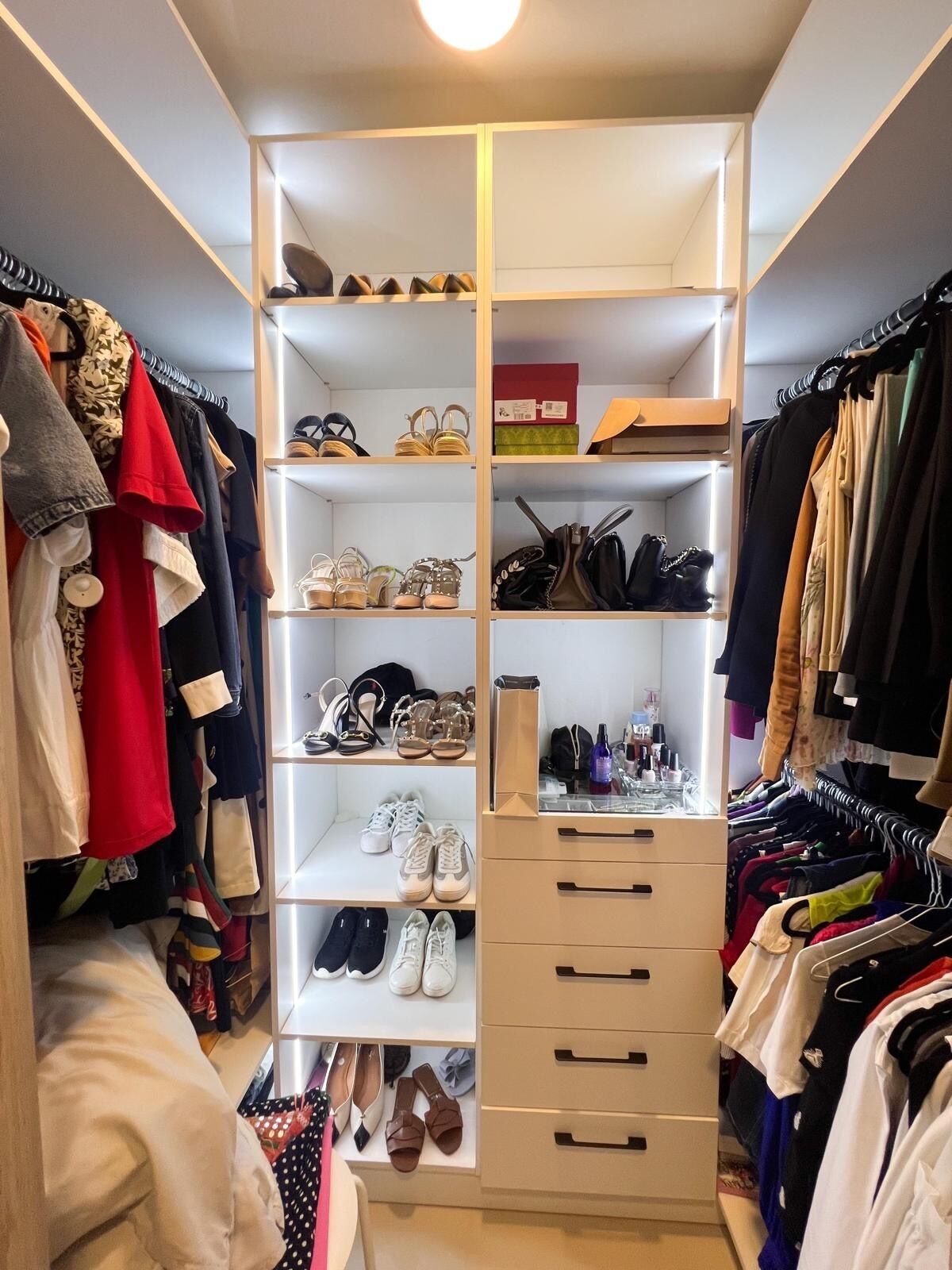 Um closet espaçoso com várias prateleiras para sapatos e gavetas para roupas dobradas.
