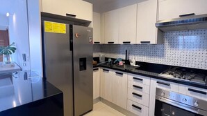 A modern kitchen with stainless steel appliances, white cabinets, and a black countertop. - Quiet and cozy place (Santo Domingo)