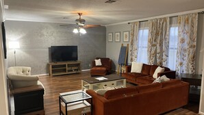 Un soggiorno con divano, tavolino, televisore e ventilatore a soffitto.